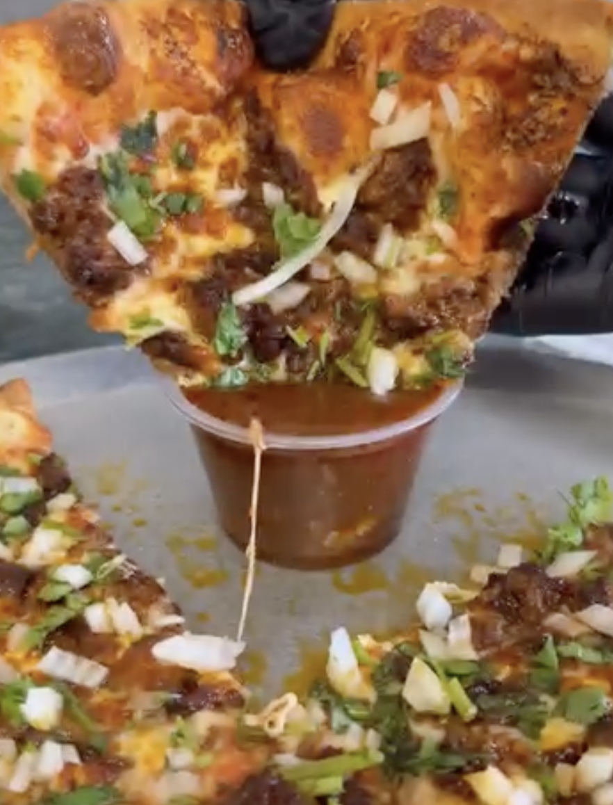 A slice of Annie's pizza dipped into rich sauce